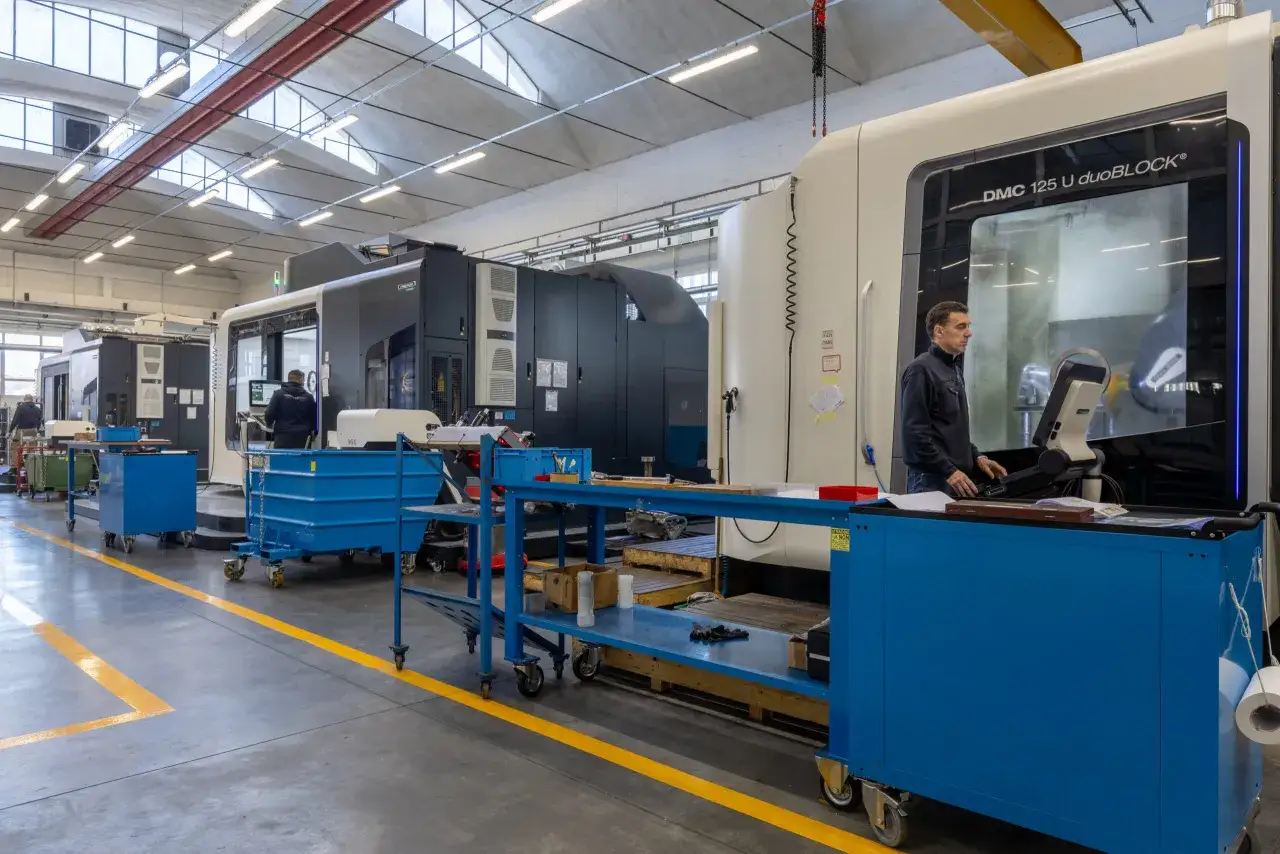 Operaio controlla una macchina DMC 125 U duoBLOCK, un centro di lavoro di precisione Mori Seiki, in un'officina moderna.