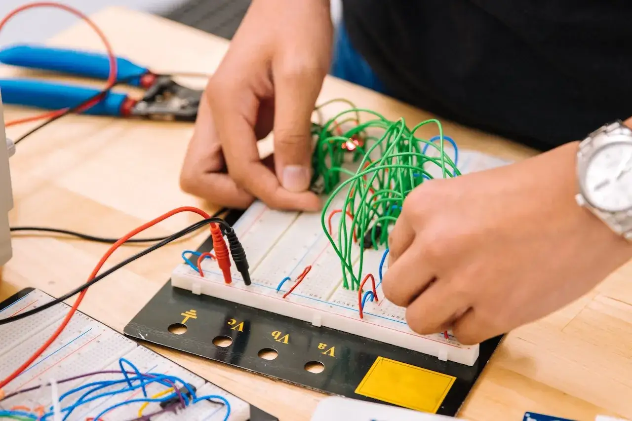 Mani che assemblano circuiti su breadboard, un'attivit&agrave; che fa riflettere su quanto guadagna un meccanico industriale.