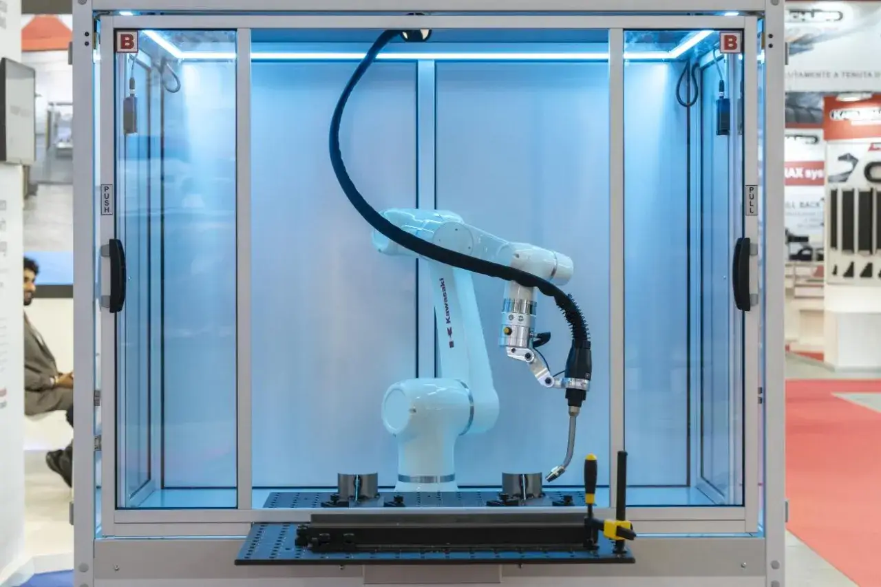 Braccio robotico Kawasaki pronto per il saldatura robotica all'interno di una cabina illuminata.