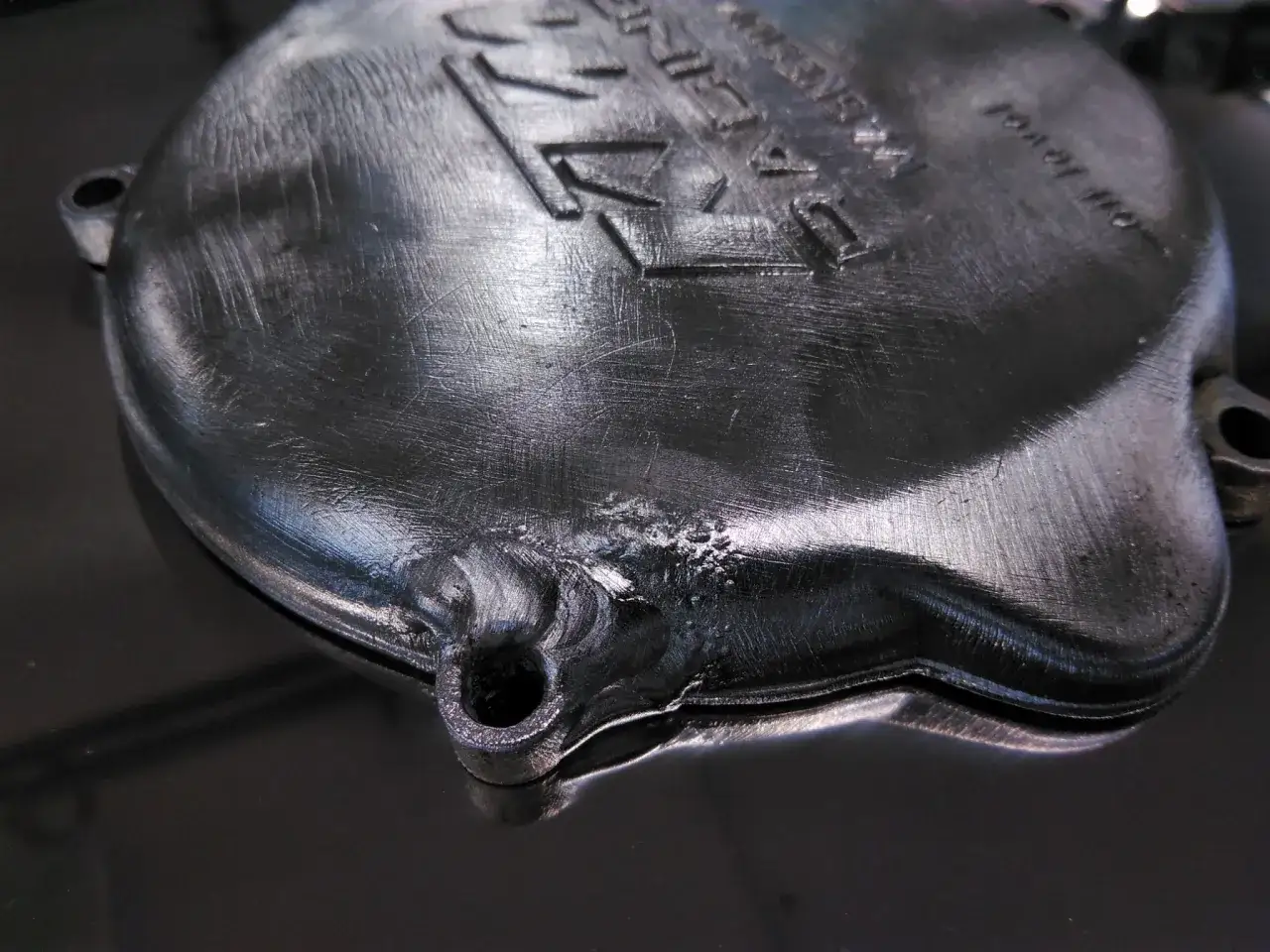 Dettaglio di una saldatura magnesio su un coperchio metallico con incisioni.